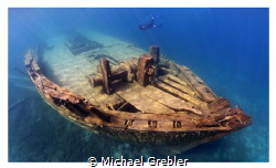 A skin diver swims down the port side of the wreck of the... by Michael Grebler 
